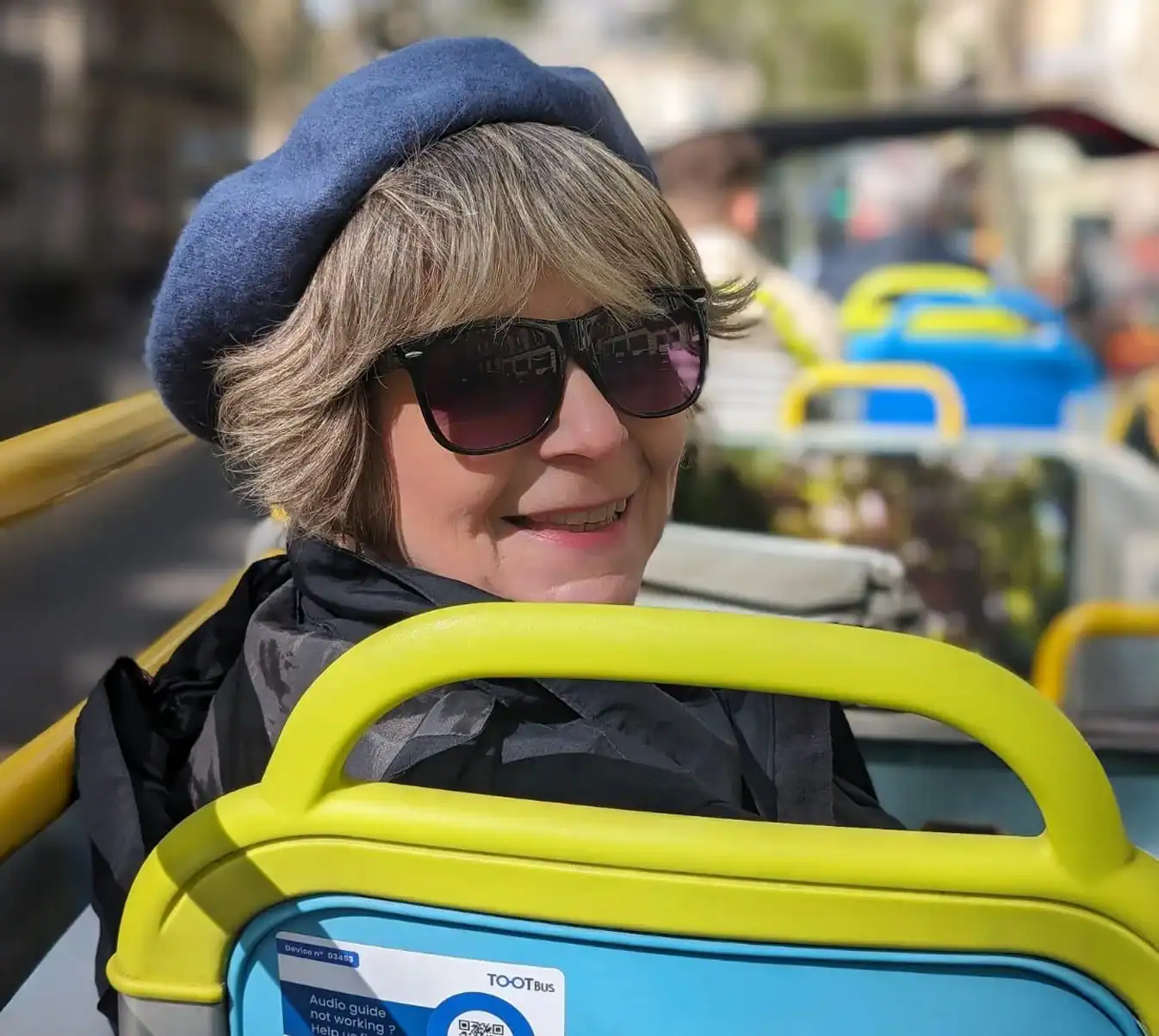 Smiling woman on a tour bus with beret.