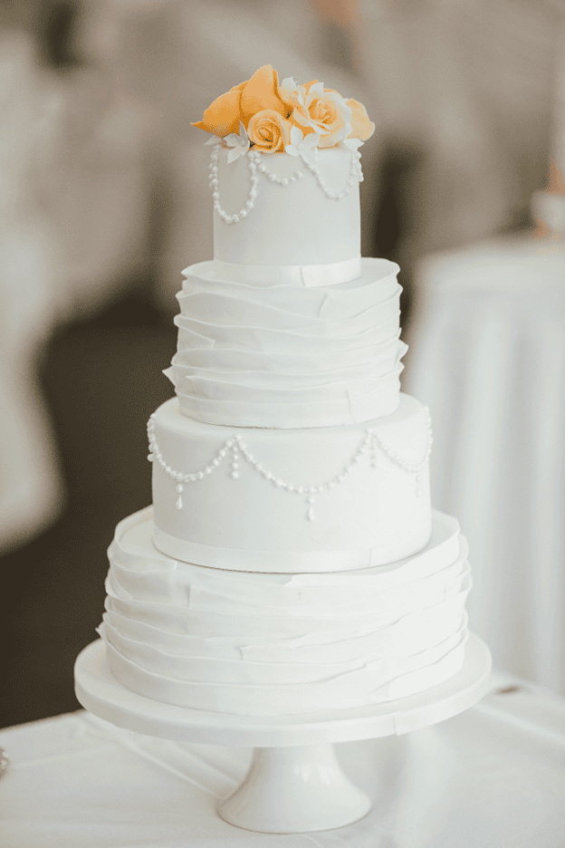 Three-tiered white wedding cake with orange roses.