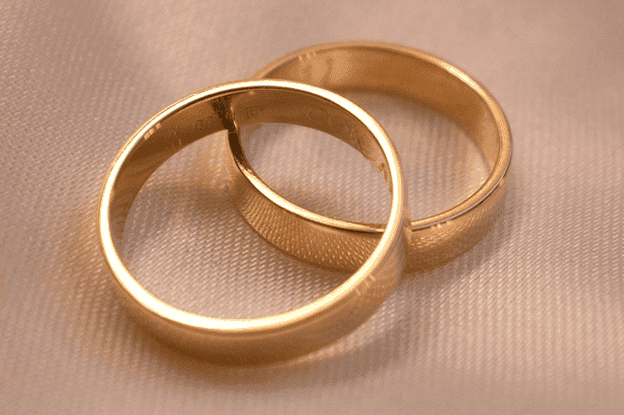 Close-up of two gold wedding rings on fabric.