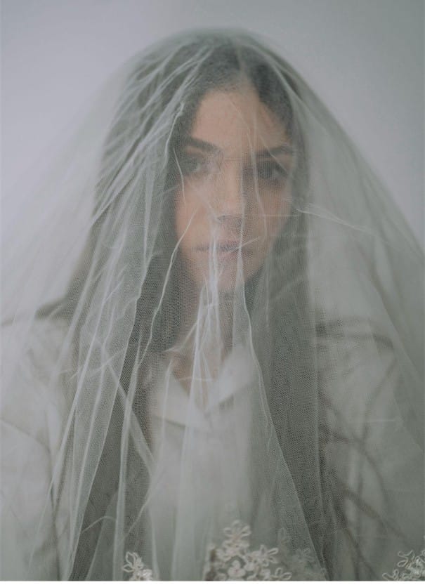 Bride with veil covering face, soft focus portrait.